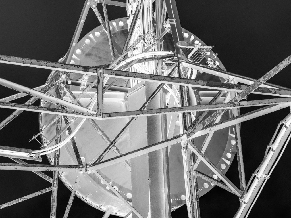 Close-up view of a tall metal structure, featuring a circular platform and intricate support beams, captured in black and white.