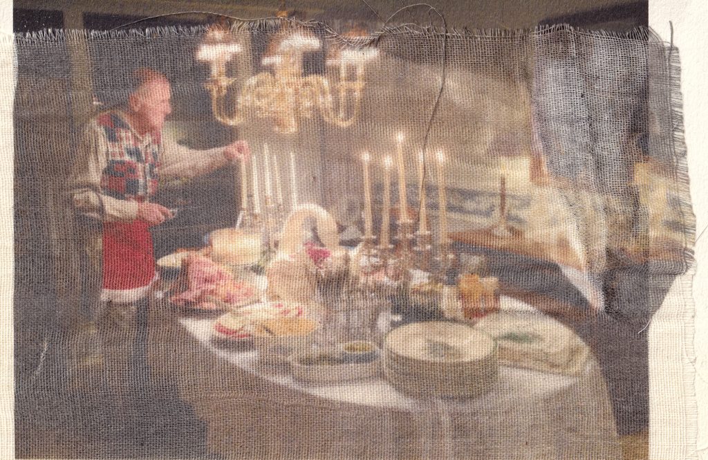 A man in a colorful sweater setting a festive dinner table with candles and food items.