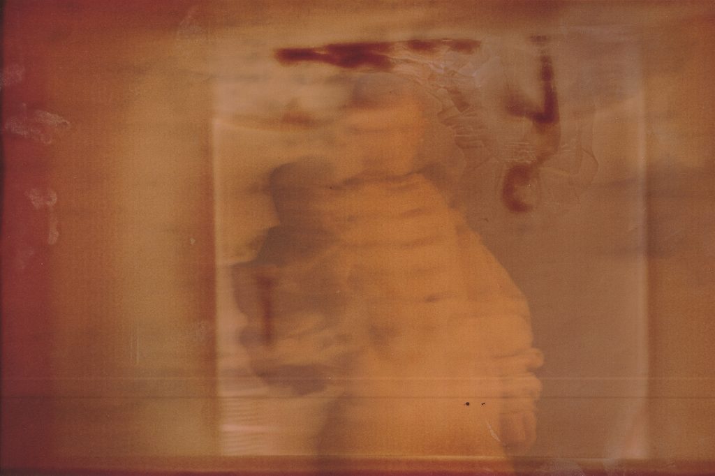 A blurred sepia-toned image featuring an indistinct figure, creating an abstract and ethereal effect.