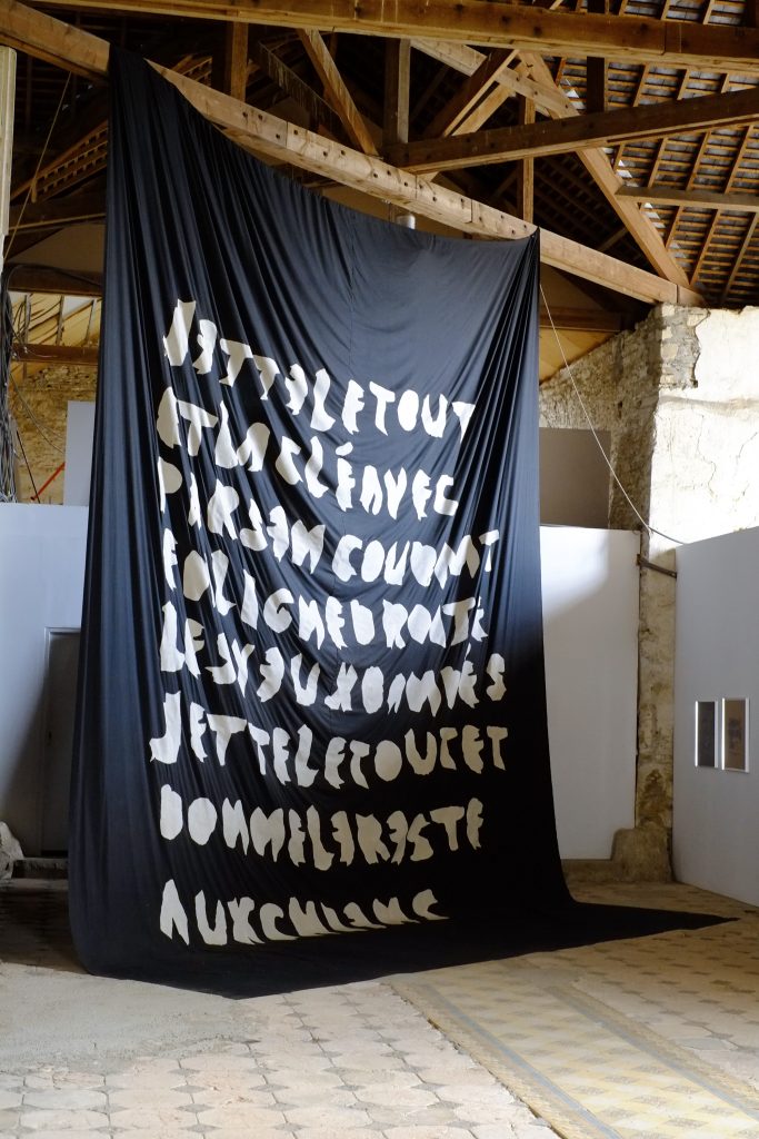 A large black banner with bold white text displayed in an art exhibition space.