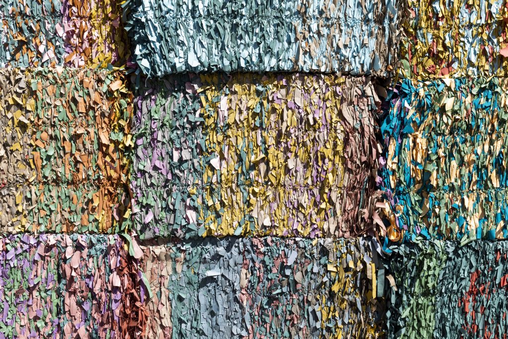 Close-up of a textured surface made of colorful shredded paper, arranged in blocks with various pastel shades.