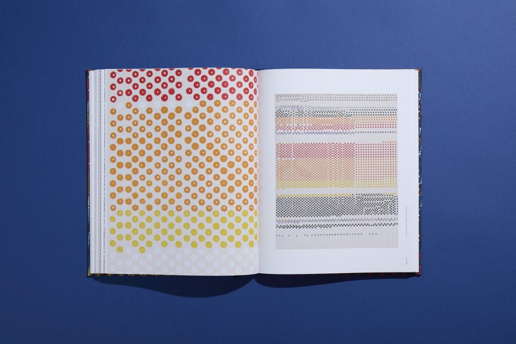An open book displaying two pages with colorful dot patterns, showcasing a gradient of colors from red to yellow on the left and a structured dot layout on the right, set against a blue background.