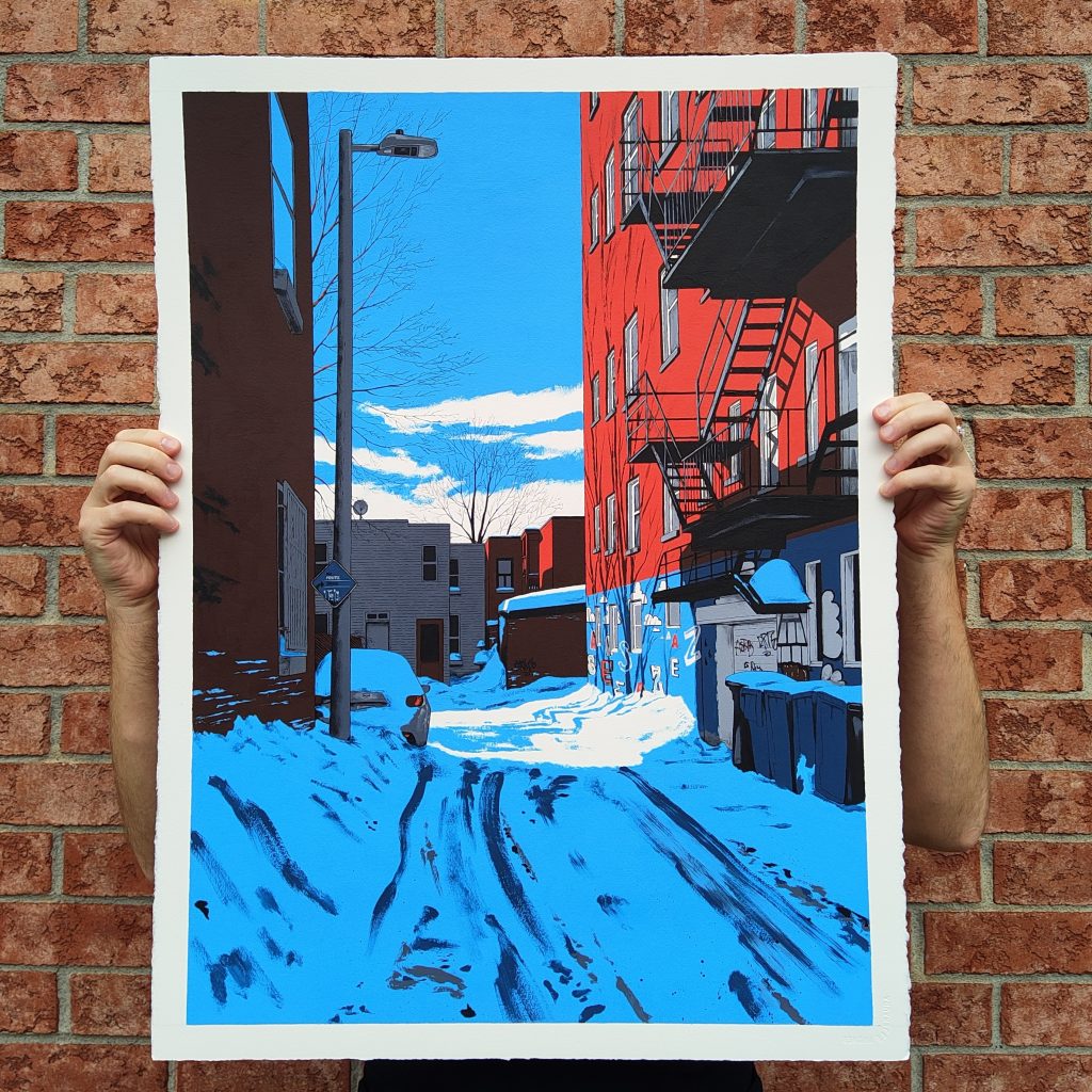 A person holding an artwork depicting a snowy alleyway with red brick buildings, streetlights, and blue sky.