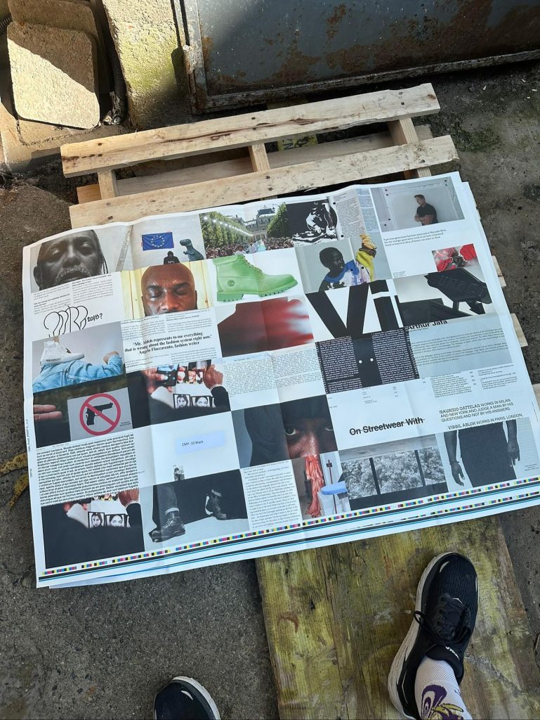 An open newspaper spread showcasing various images and articles related to streetwear, including photographs, graphics, and text, placed on a wooden pallet in an outdoor setting.