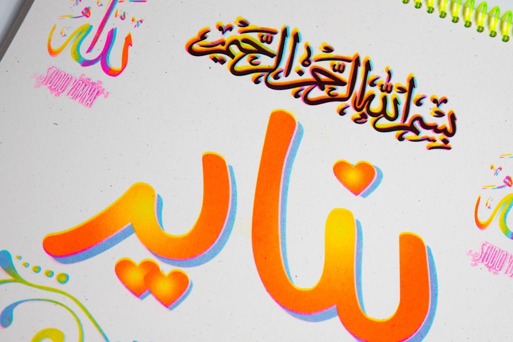Colorful artistic representation of Arabic calligraphy with a heart shape, featuring the word 'ناديه' and decorative elements on a light background.