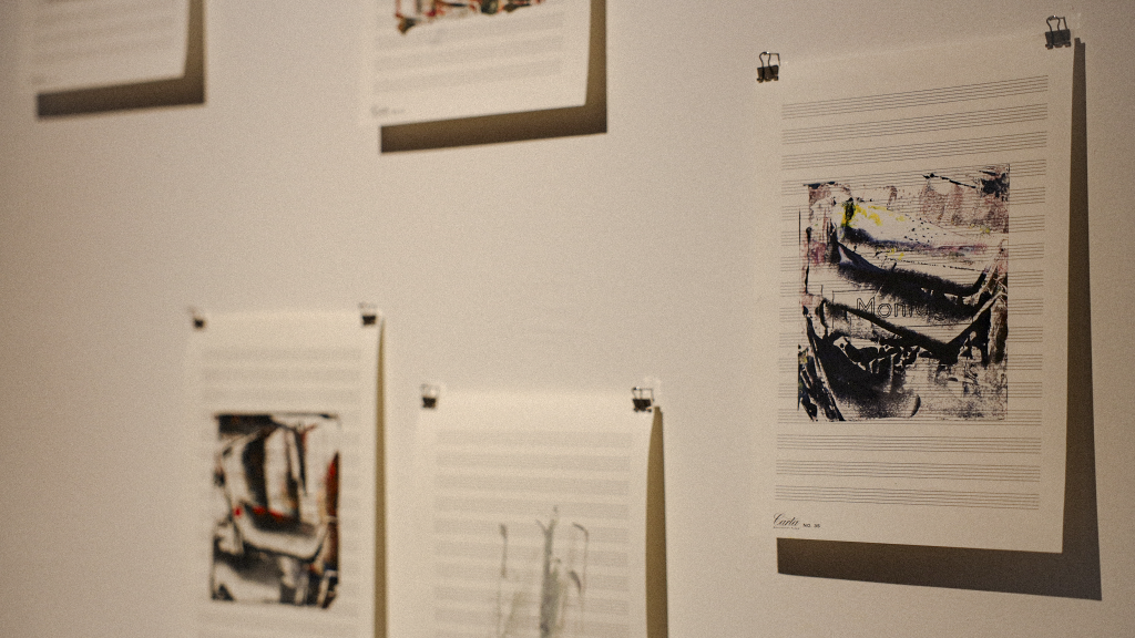 Artworks displayed on a white wall, featuring a mix of abstract prints and illustrations secured with clips.